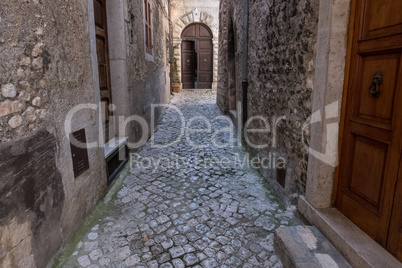 Wooden ajar door at the end of an alley in a medieval town.