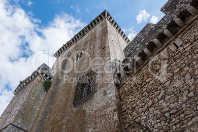 Tower window of an ancient stone castle with blue sky and clouds