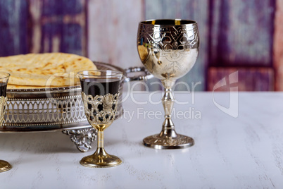 Taking Communion. Cup of glass with red wine, bread on wooden table focus on wine