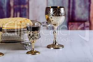 Taking Communion. Cup of glass with red wine, bread on wooden table focus on wine