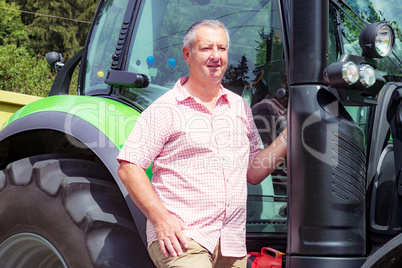 Farmer stands beside his tractor