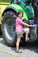 Farmer is standing next to her tractor