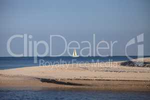 Sailboat glides across the bright blue ocean