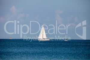 Sailboat glides across the bright blue ocean