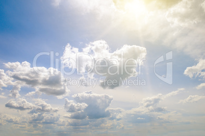 Sun on blue sky with white clouds.