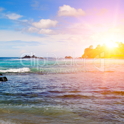 Sea landscape with rocky island and the sunrise. Beach.