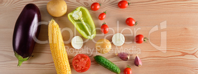 A set of vegetables laid out on a wooden table. Wide photo.