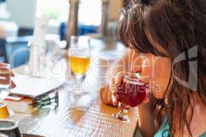 Female Sipping Glass of Micro Brew Beer At Bar With Friends