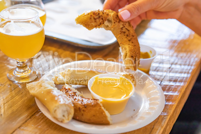 Woman Dips Warm Pretzel in Cheese with Micro Brew Beer