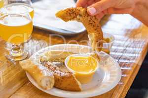 Woman Dips Warm Pretzel in Cheese with Micro Brew Beer