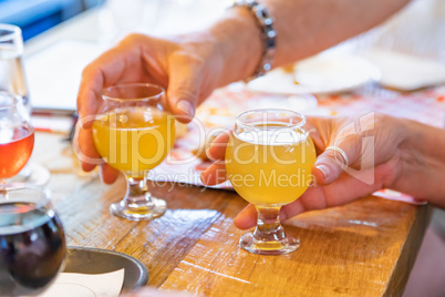 Man and Woman Picking Up Small Glass of Micro Brew Beer at Bar
