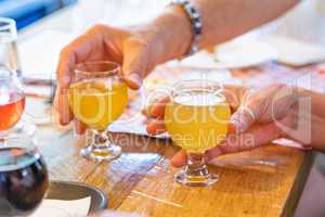 Man and Woman Picking Up Small Glass of Micro Brew Beer at Bar