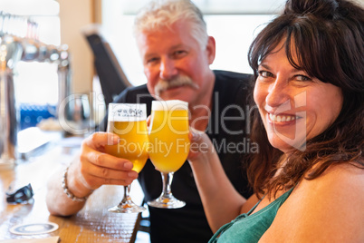 Attractive Middle-Aged Couple Toasting Glasses of Micro Brew Beer