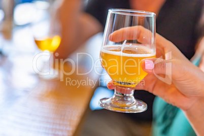 Female Hand Holding Glass of Micro Brew Beer At Bar