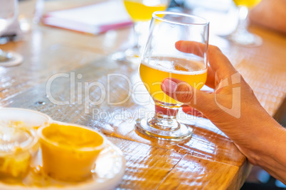 Female Hand Holding Glass of Micro Brew Beer At Bar