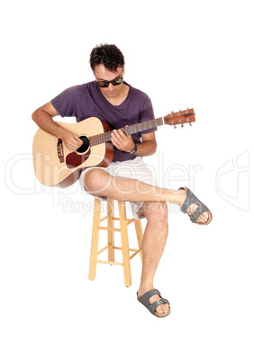 Young man sitting and playing his guitar