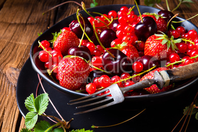 Bowl with different fruits such as strawberry, red currant, and