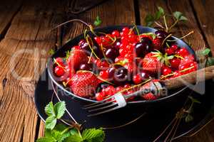 Bowl with different fruits such as strawberry, red currant, and