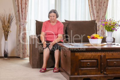 Elderly woman suffering from pain in knee at home