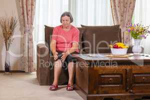 Elderly woman suffering from pain in knee at home