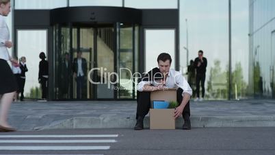 Fired business man sitting on the street