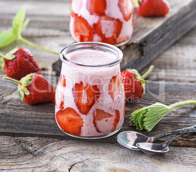 ripe red strawberry and two glass jars of smoothies