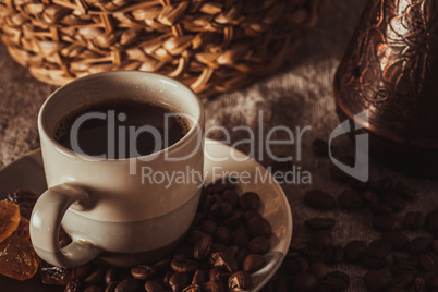 cup of coffee on textile with beans, dark candy sugar, pots, basket