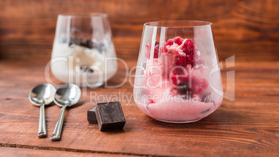White and pink ice cream in glass on wooden table