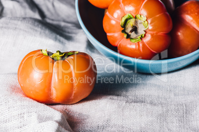 One Persimmon Near the Bowl of Persimmons