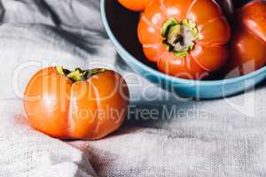One Persimmon Near the Bowl of Persimmons