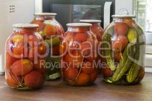 Canned tomatoes and cucumbers in large glass jars.