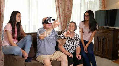 Senior man in virtual reality headset or 3d glasses having fun with family