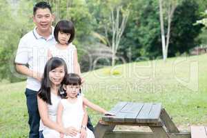 Asian family outdoors portrait with empty table space.