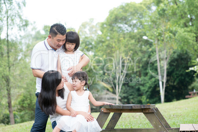 Happy Asian family outdoor portrait with empty table space.