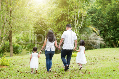 Asian family walking at outdoor park, back view.