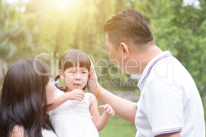 Parents comfort crying daughter outdoors