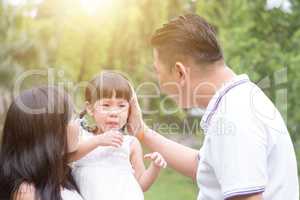 Parents comfort crying daughter outdoors