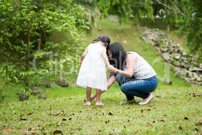 Mother helps little girl wearing shoe