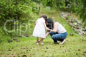 Mother helps little girl wearing shoe