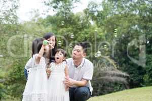 Family blowing soap bubbles outdoors