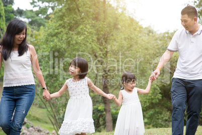 Asian family hold hands and walking at outdoor park.