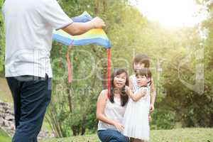 Asian family flying kite outdoors.