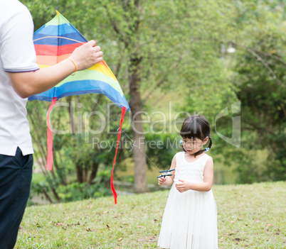 Asian family flying kite at park.