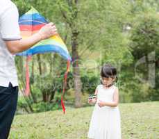 Asian family flying kite at park.