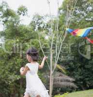 Little girl flying kite at park.