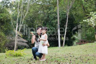 Mother and daughter blowing soap bubbles