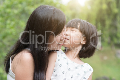 Little girl kissing mom at outdoor park