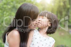 Little girl kissing mom at outdoor park
