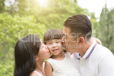 Parents kissing child at outdoor park