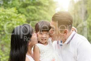 Parents kissing child outdoors
